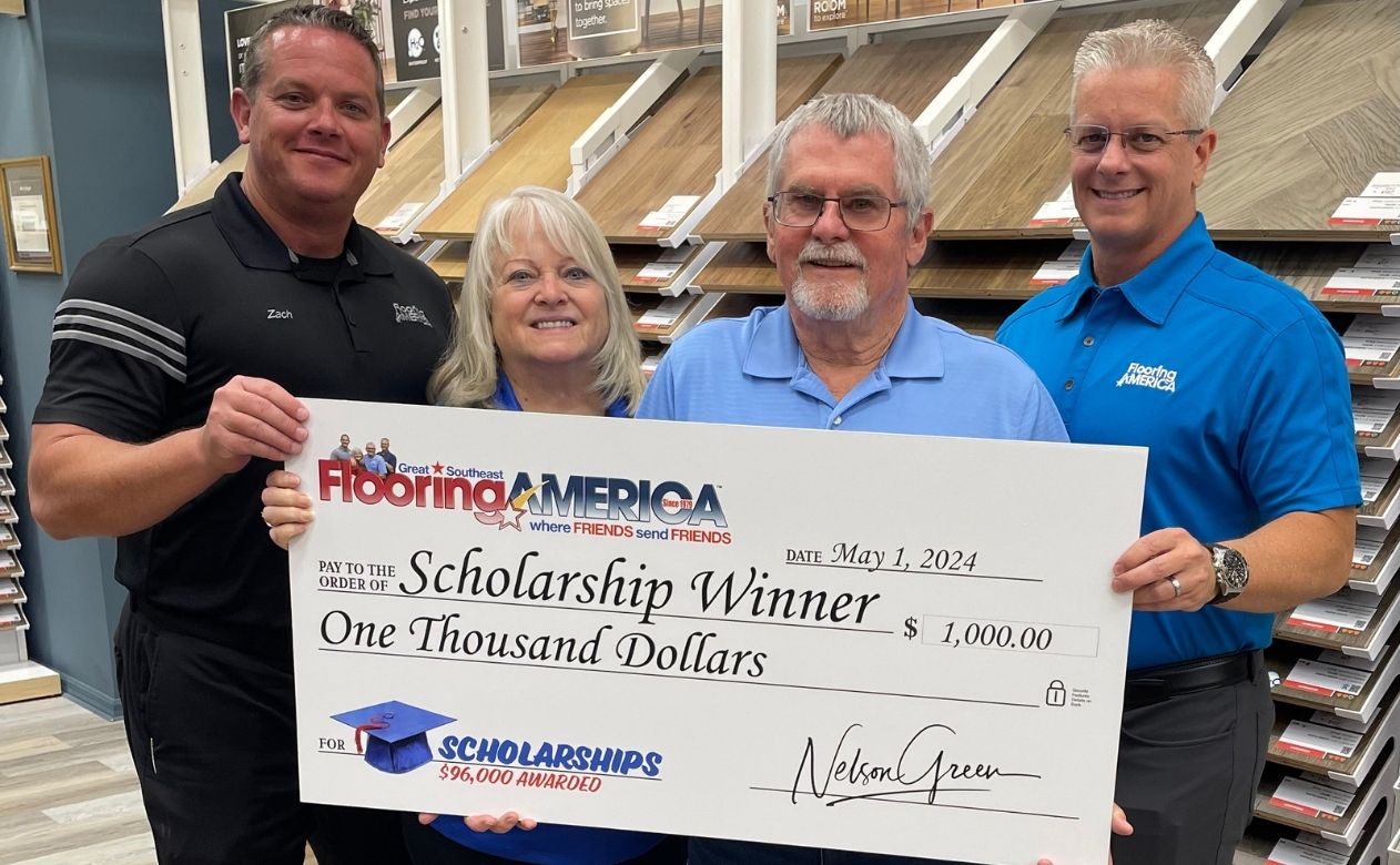 Family business owners in showroom holding scholarship donation check