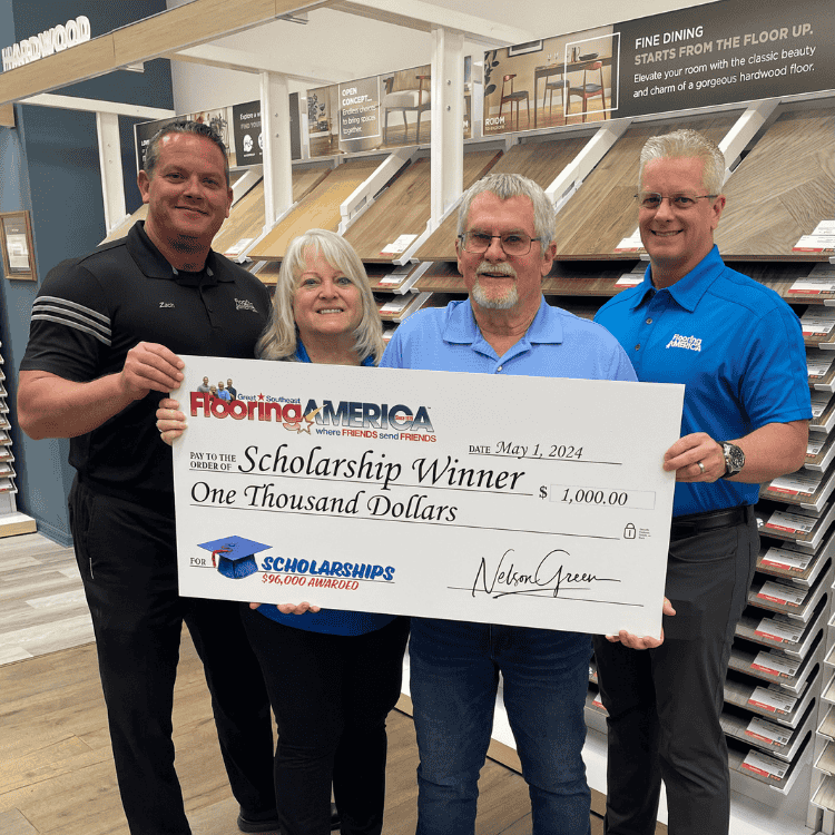 Family business owners in showroom holding scholarship donation check